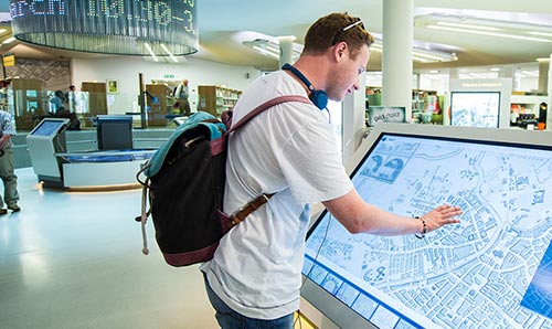 young man exploring a digital map in Manchester Centre Library